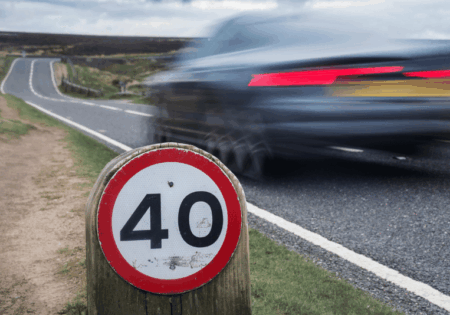 Speed limit sign on rural road with car