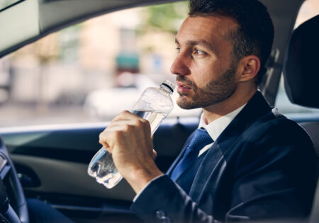 Kind young bearded man drinking mineral water